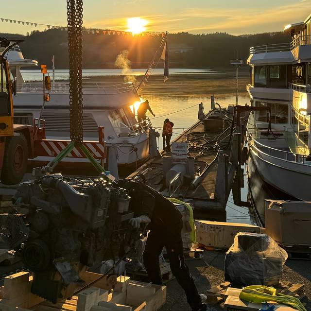 Ein Kran hebt einen Dieselmotor aus dem Schiff
