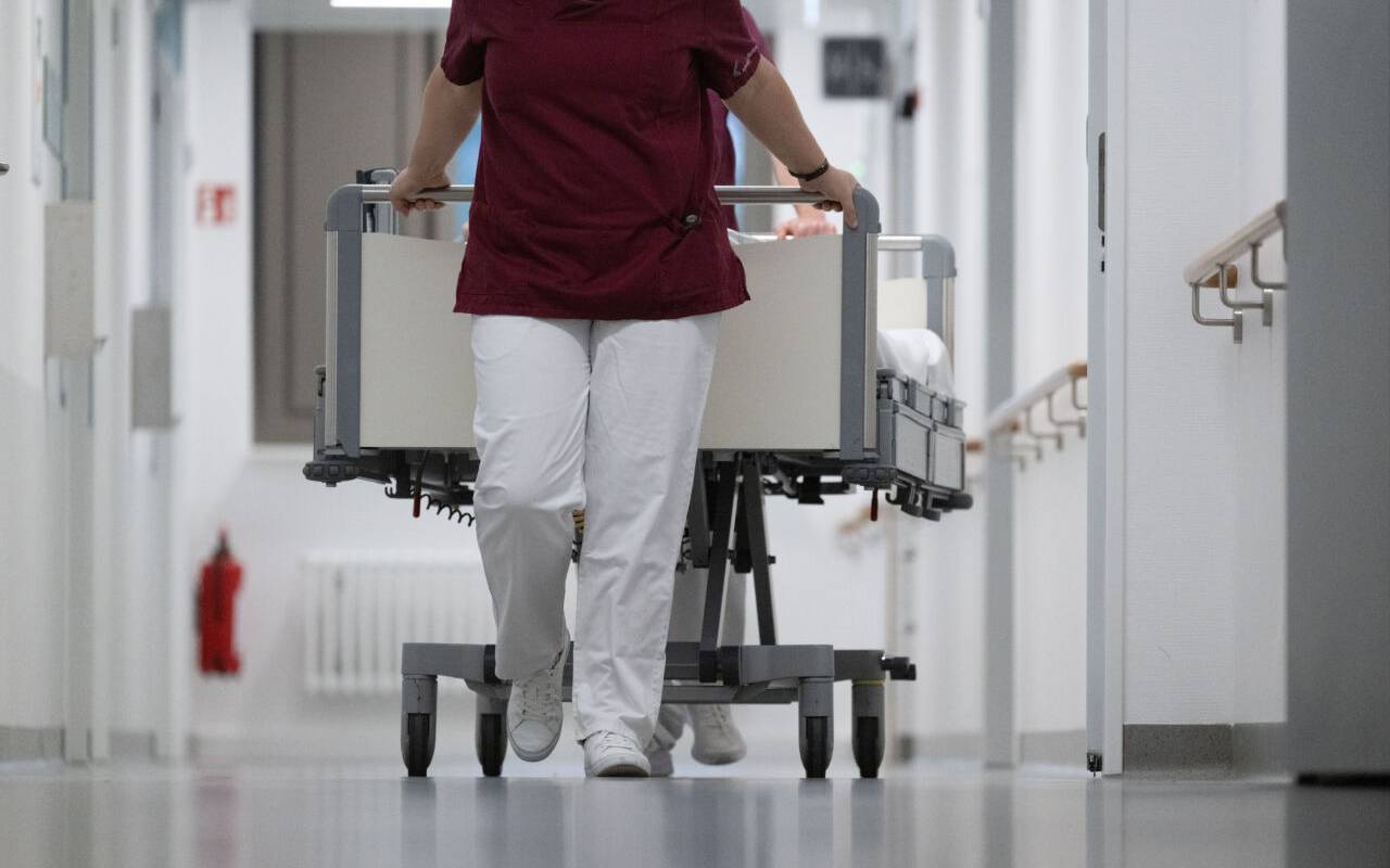 In einem Krankenhaus schiebt eine Krankenschwester ein Bett vor sich her.