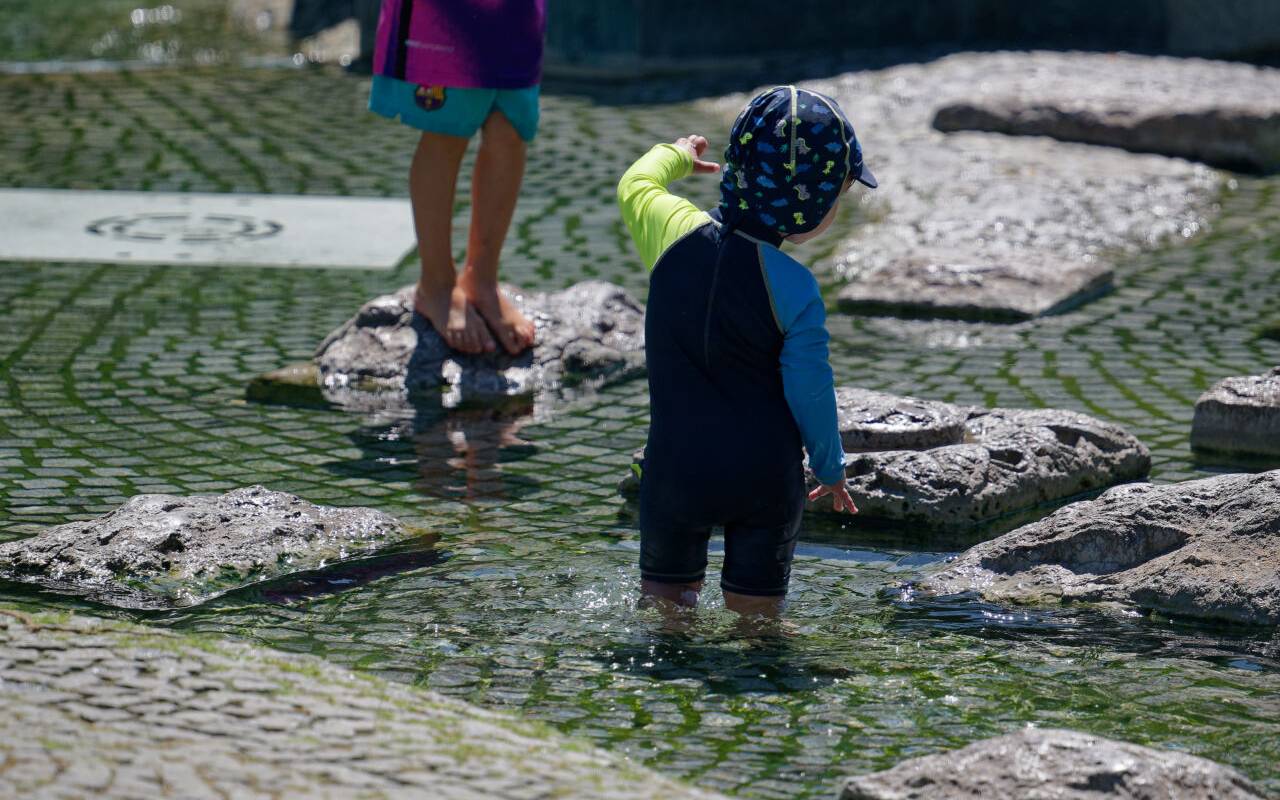 Kinder kühlen sich in einem Brunnen nahe des Rheins ab.