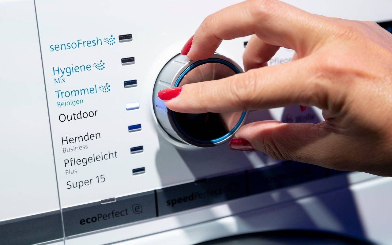 Eine Frau dreht einen Knopf an einer Waschmaschine