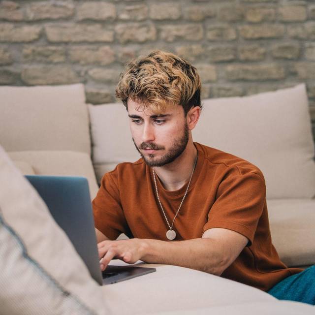 Ein Mann am Laptop auf einer Couch