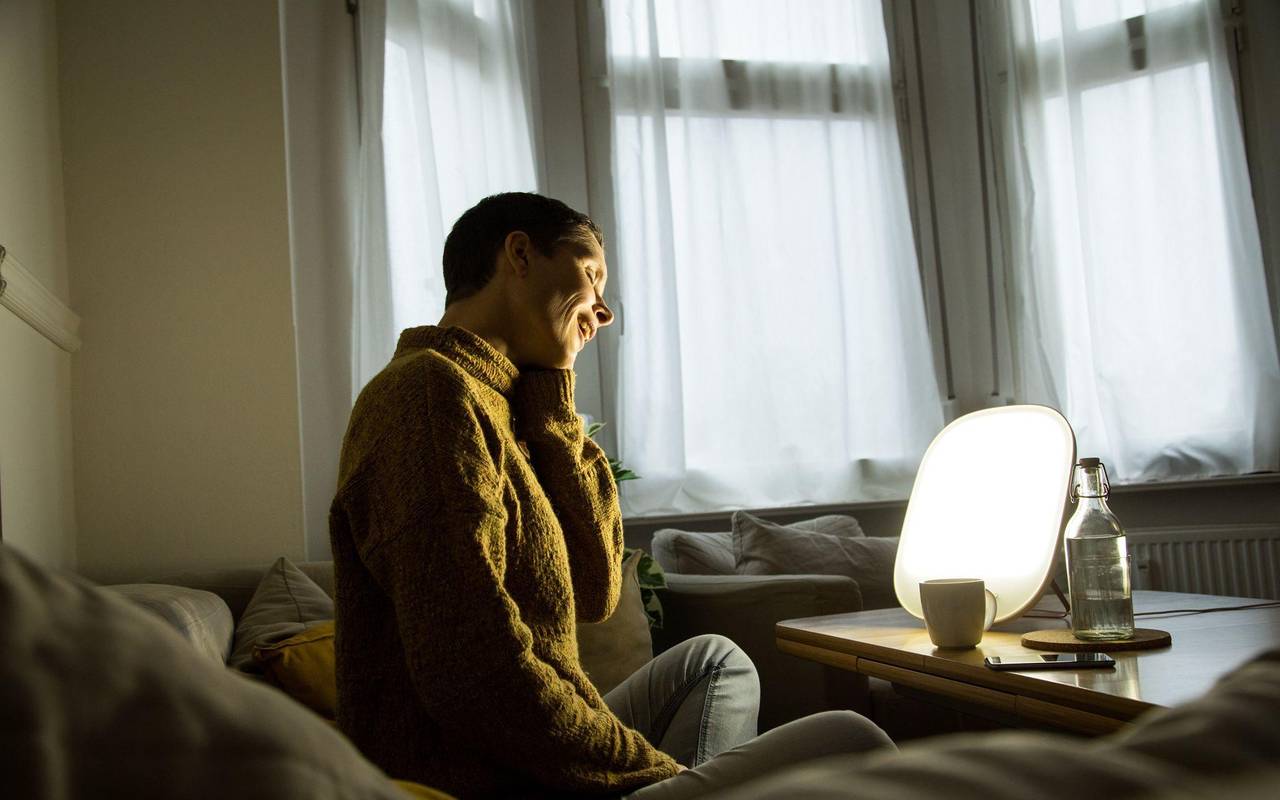 Frau sitzt vor einer Tageslichtlampe