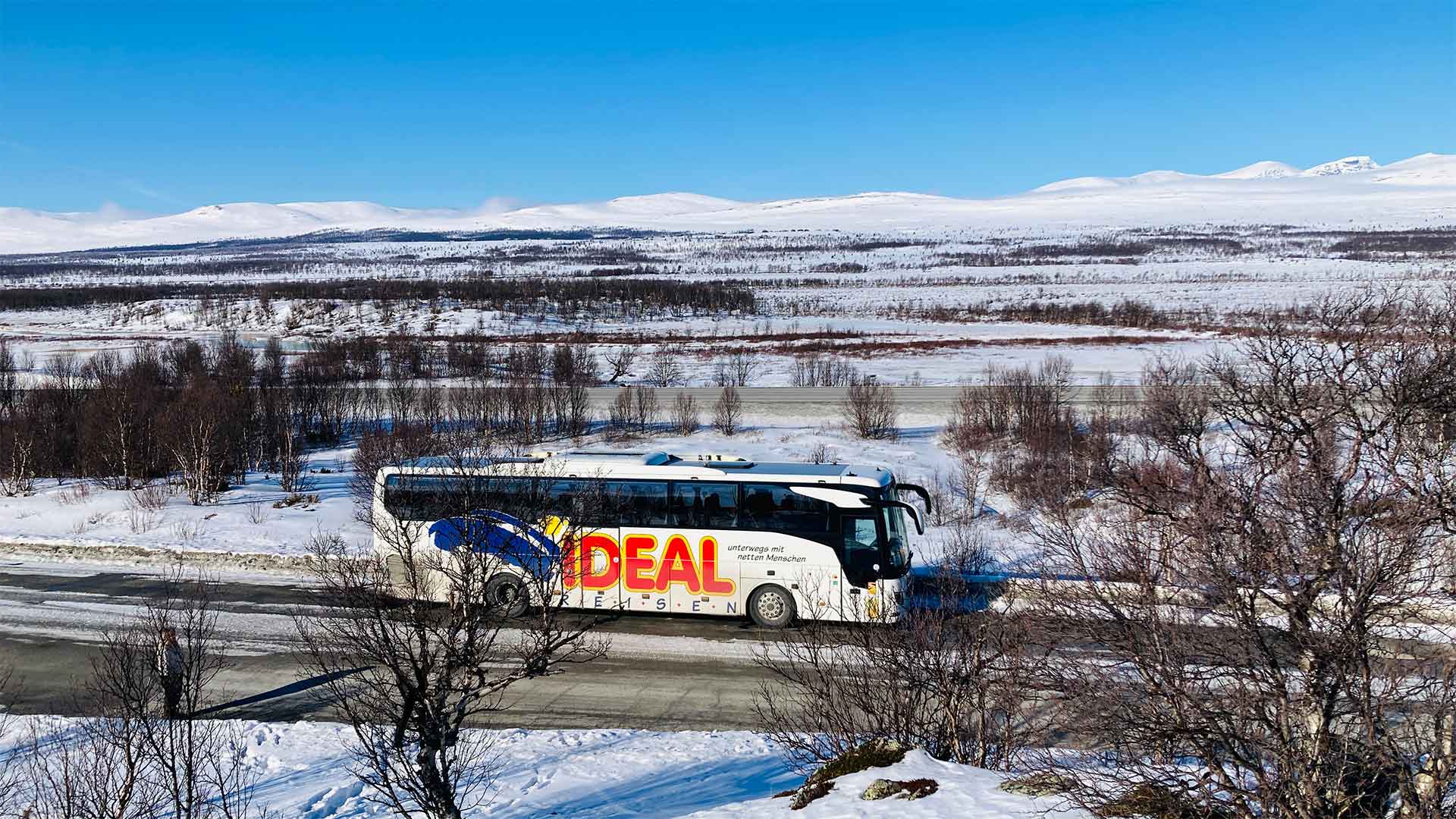 IDEAL REISEN-Bus, geparkt vor einer schönen Winterlandschaft während einer Busreise durch Skandinavien