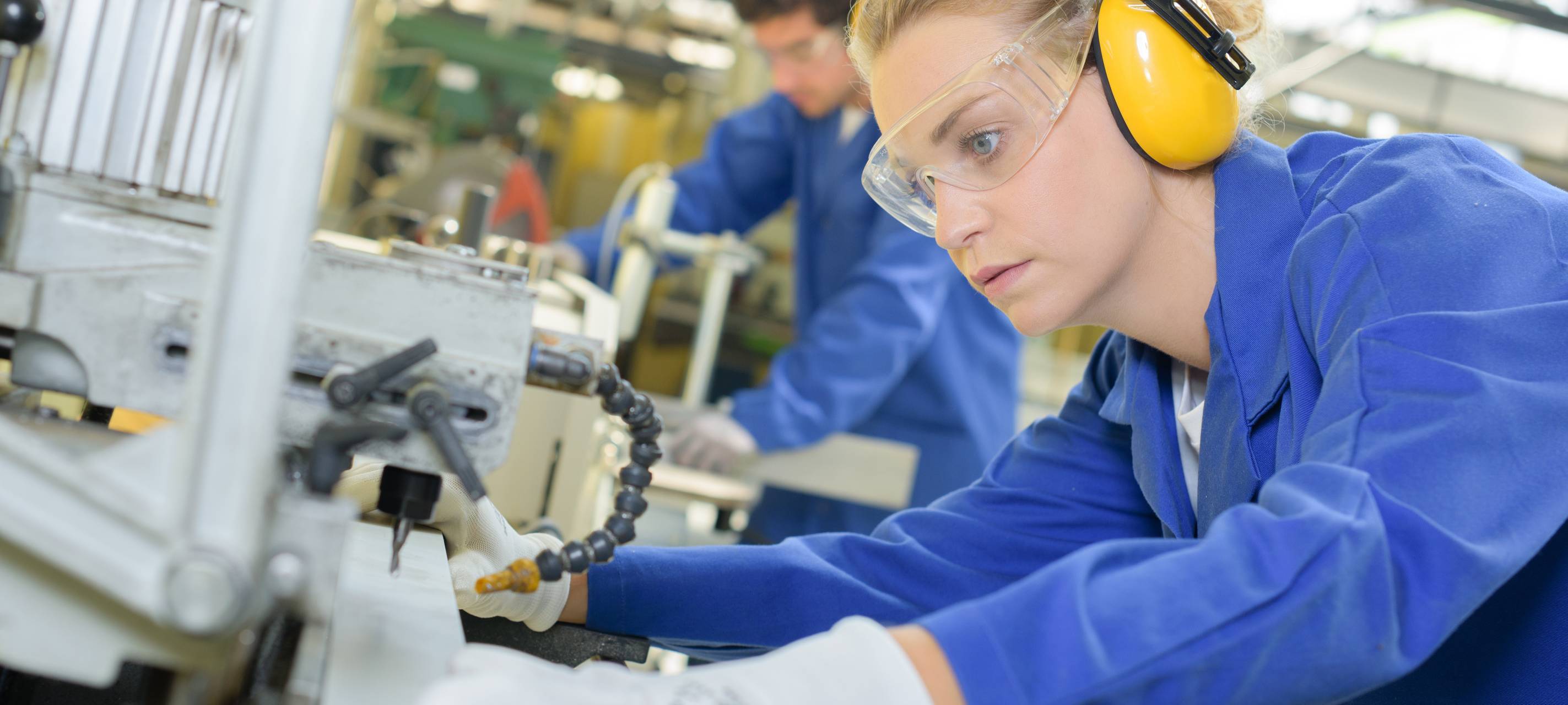 Eine Frau arbeitet an einer industriellen Fertigungsanlage (Symbolbild).