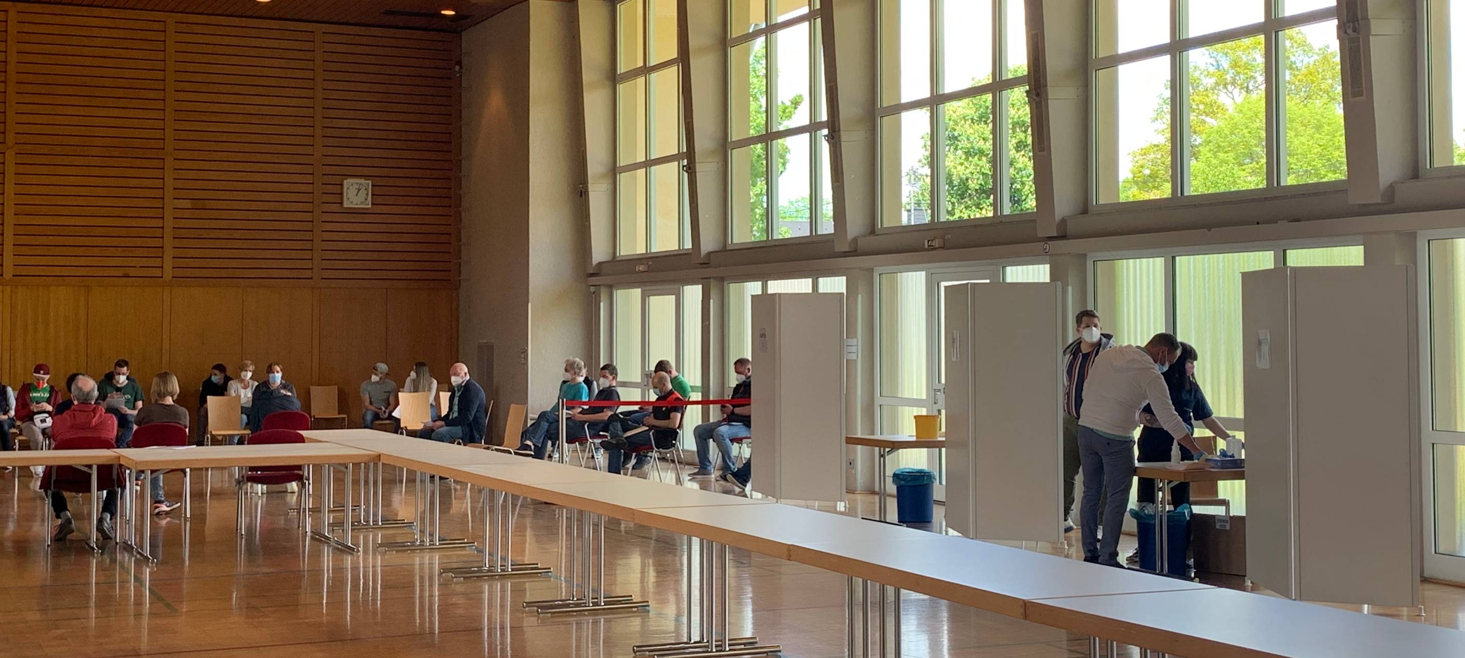 Menschen mit Masken sitzen in der Otto-Flick-Halle in Kreuztal und warten auf ihre Impfung mit AstraZeneca