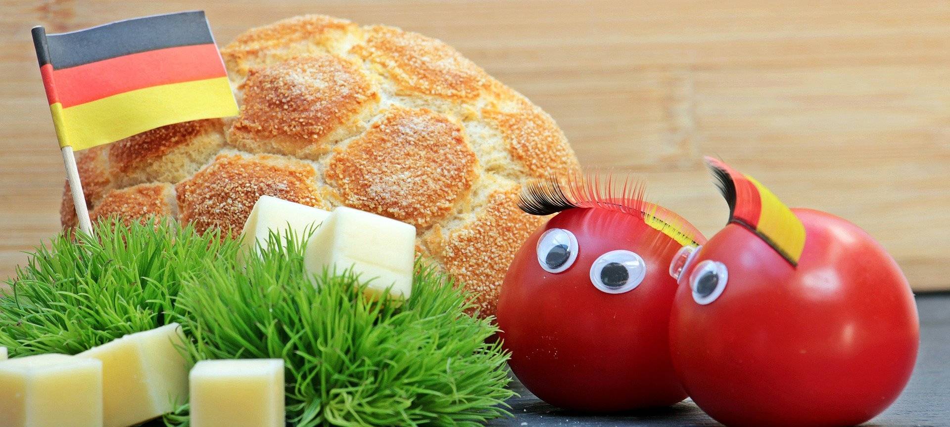 Symbolbild Public Viewing: Ein Brötchen, Käsewürfel und Tomaten, dekoriert mit schwarz-rot-goldenen Fan-Artikeln