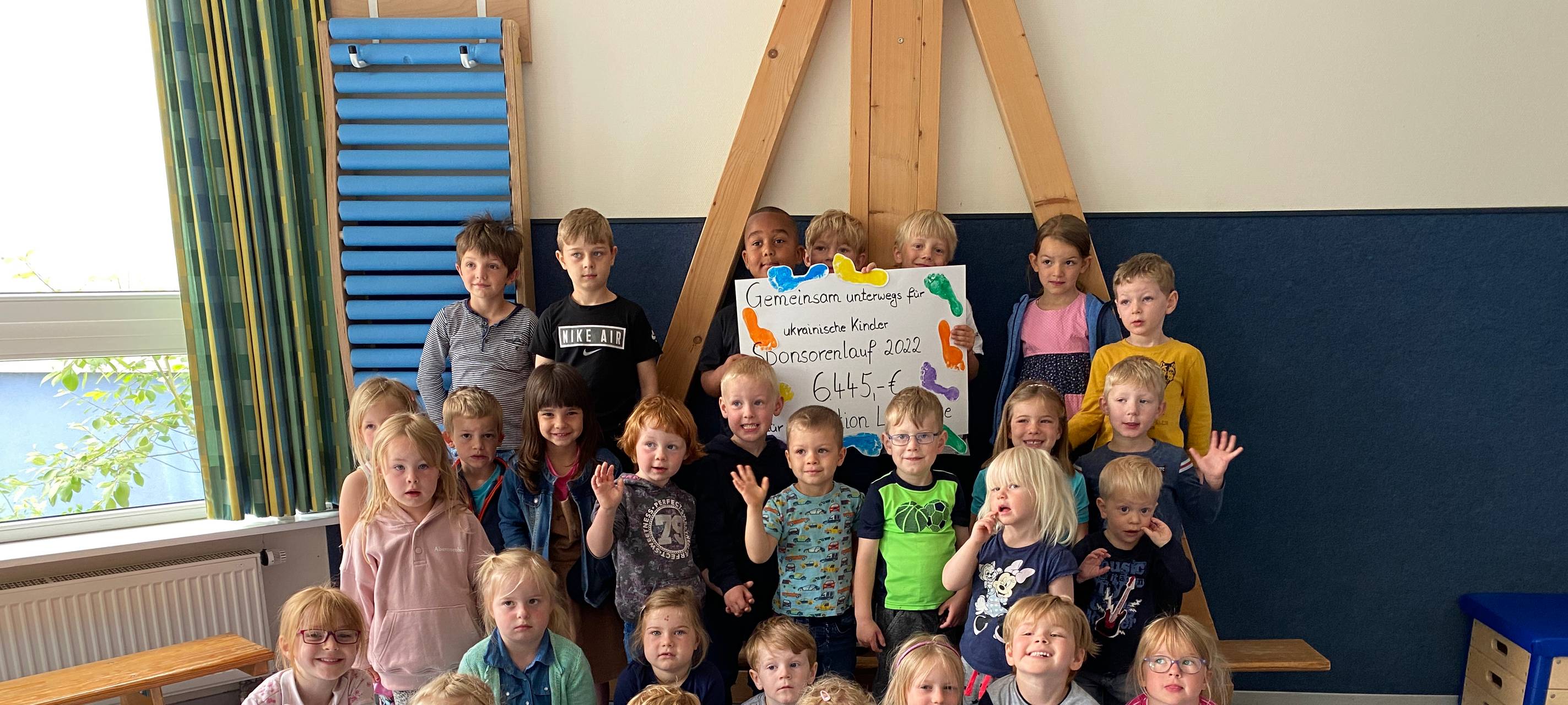 Die Kinder halten einen selbstgemachten Spendenscheck hoch
