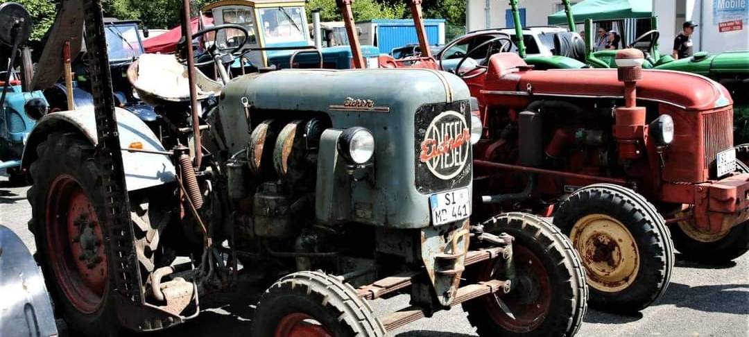 Zwei alte Trecker gut erhalten auf einem großen Parkplatz