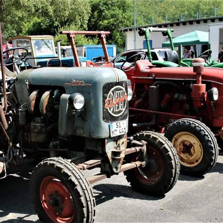 Zwei alte Trecker gut erhalten auf einem großen Parkplatz