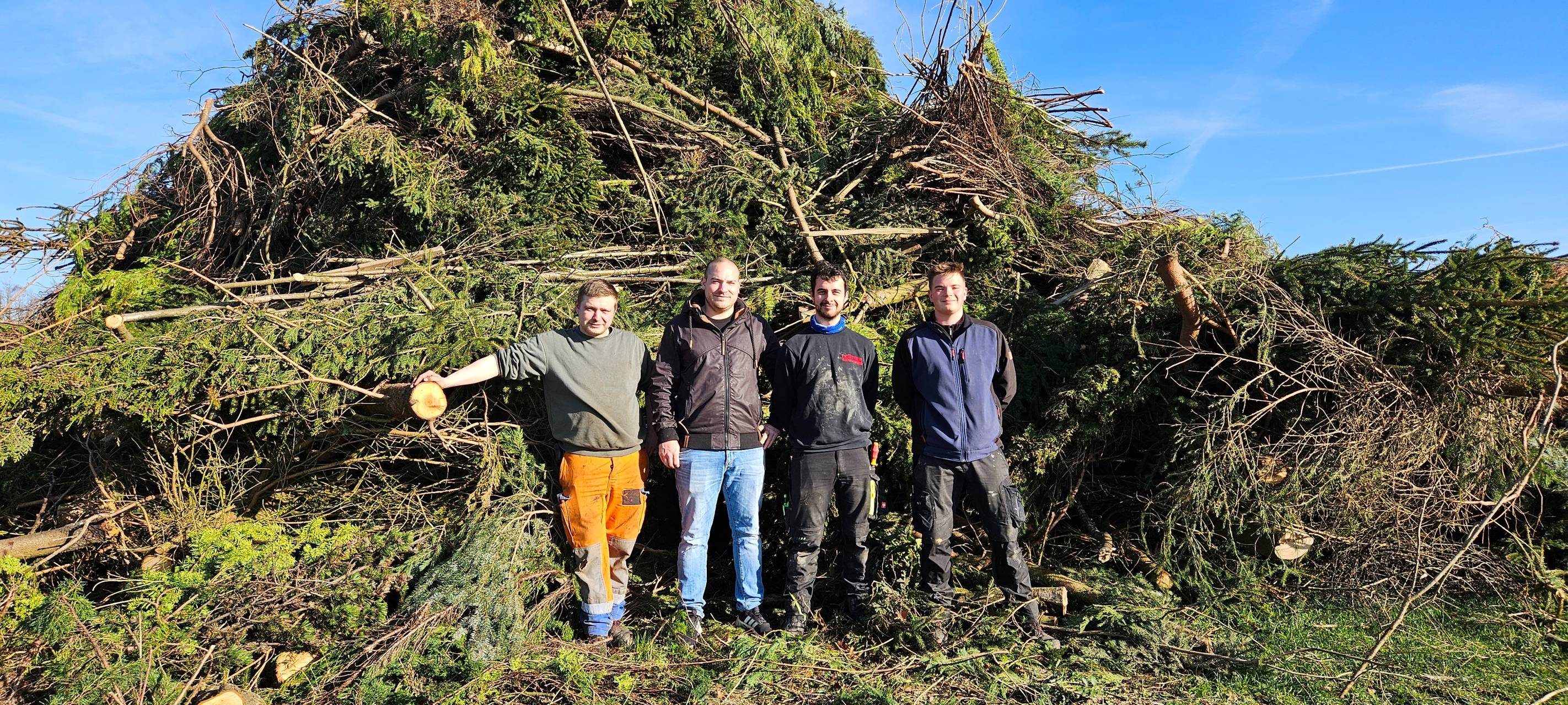 Ein großes Osterfeuer und davor vier Menschen von der Dorfjugend Schameder
