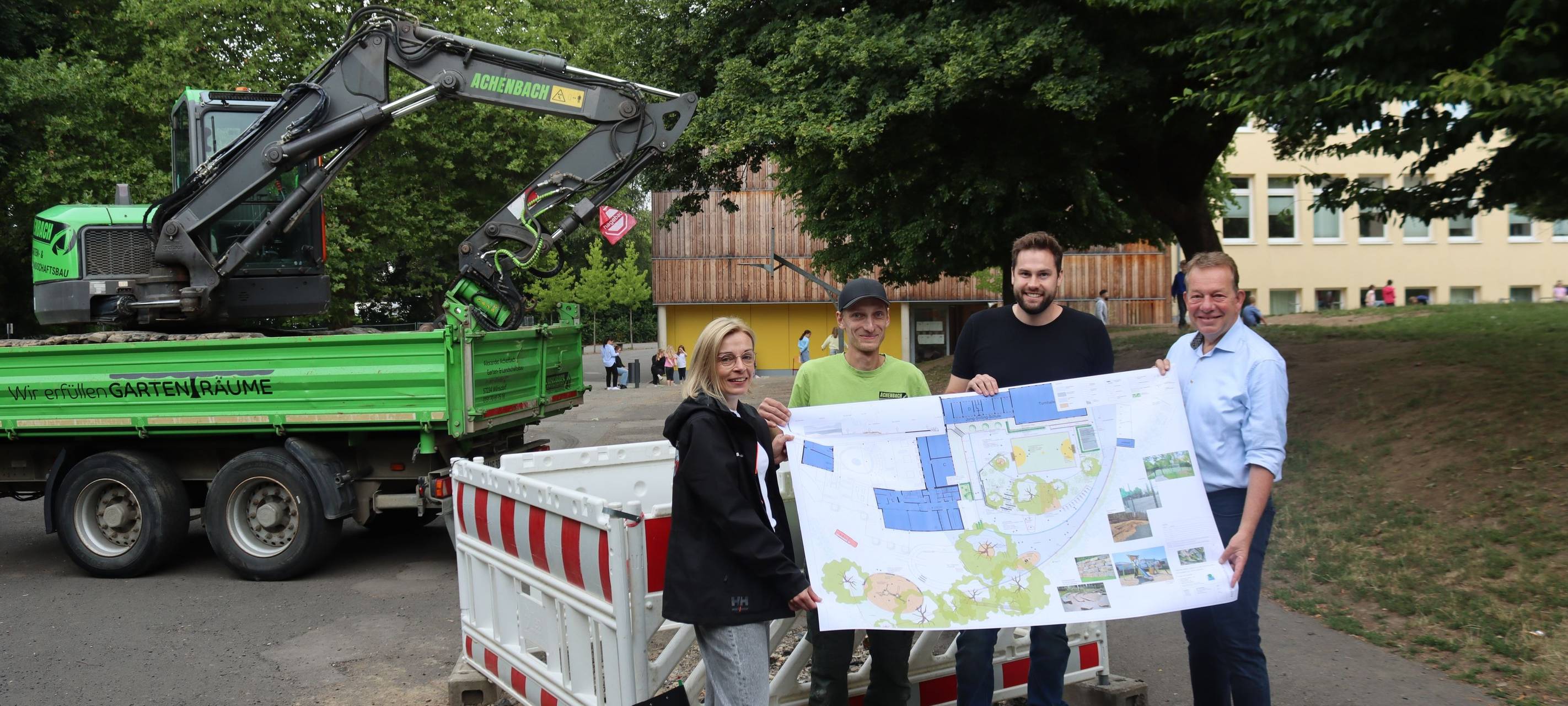 Der Bauplan zeigt viel Grün statt Grau: (v.l.) Projektleiterin Birte Grunwald (TGW), Alexander Achenbach (Garten- und Landschaftsbau), Max Laufenburg (Planungsbüro) und Bürgermeister Steffen Mues bei der Baustellen-Besichtigung an der Jung-Stilling-Schule.