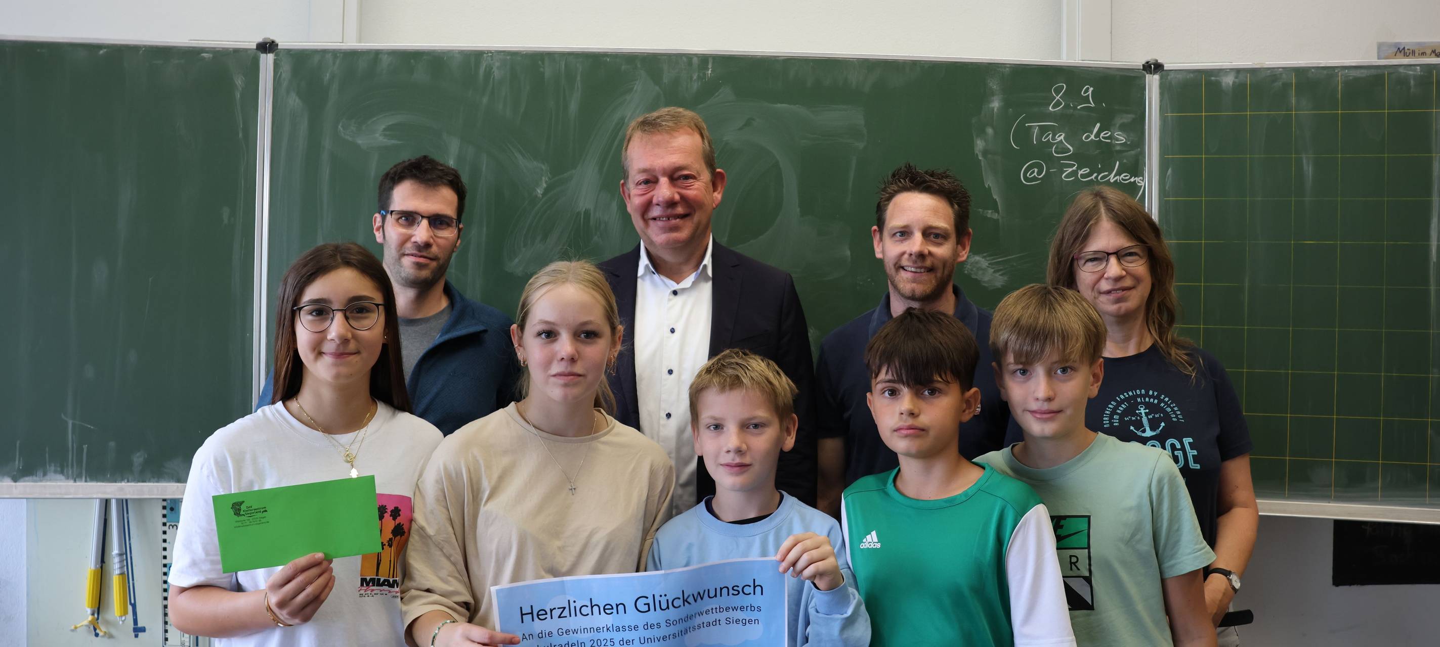 (v.l.) Hendrik Kölsch (DAV), Bürgermeister Steffen Mues, Jan König (Mobilitätsmanager) und Judith Zeller (Klassenlehrerin 7e) überreichen den Hauptpreis an die Schülerinnen und Schüler der Bertha-von-Suttner-Gesamtschule.