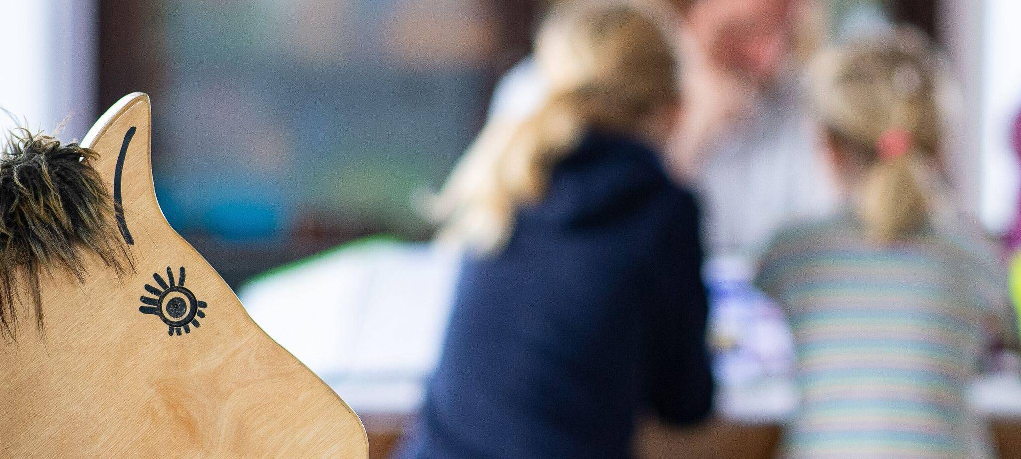 Ein Elternteil sitzt mit seinen Kindern an einem Tisch