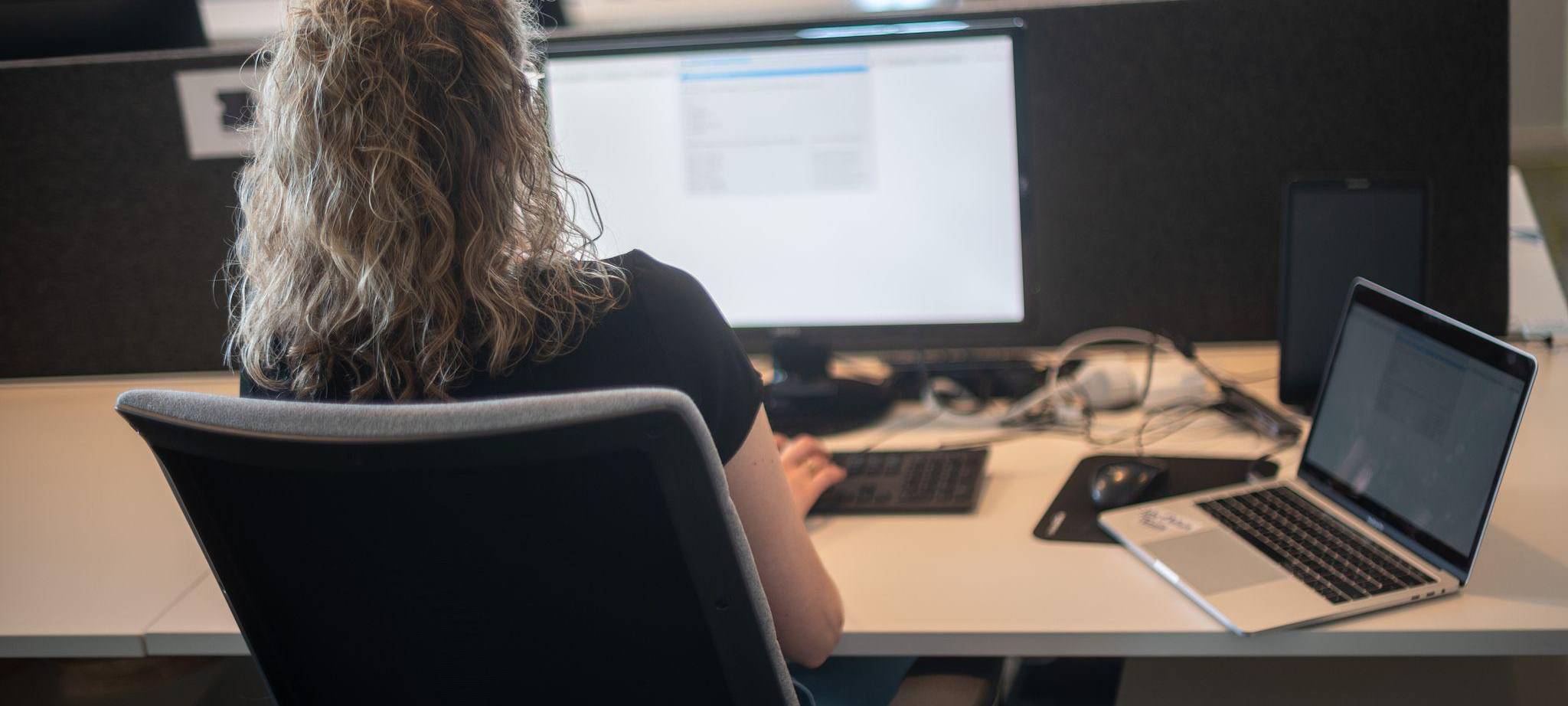 Eine Frau sitzt am Schreibtisch vor einem Bildschirm