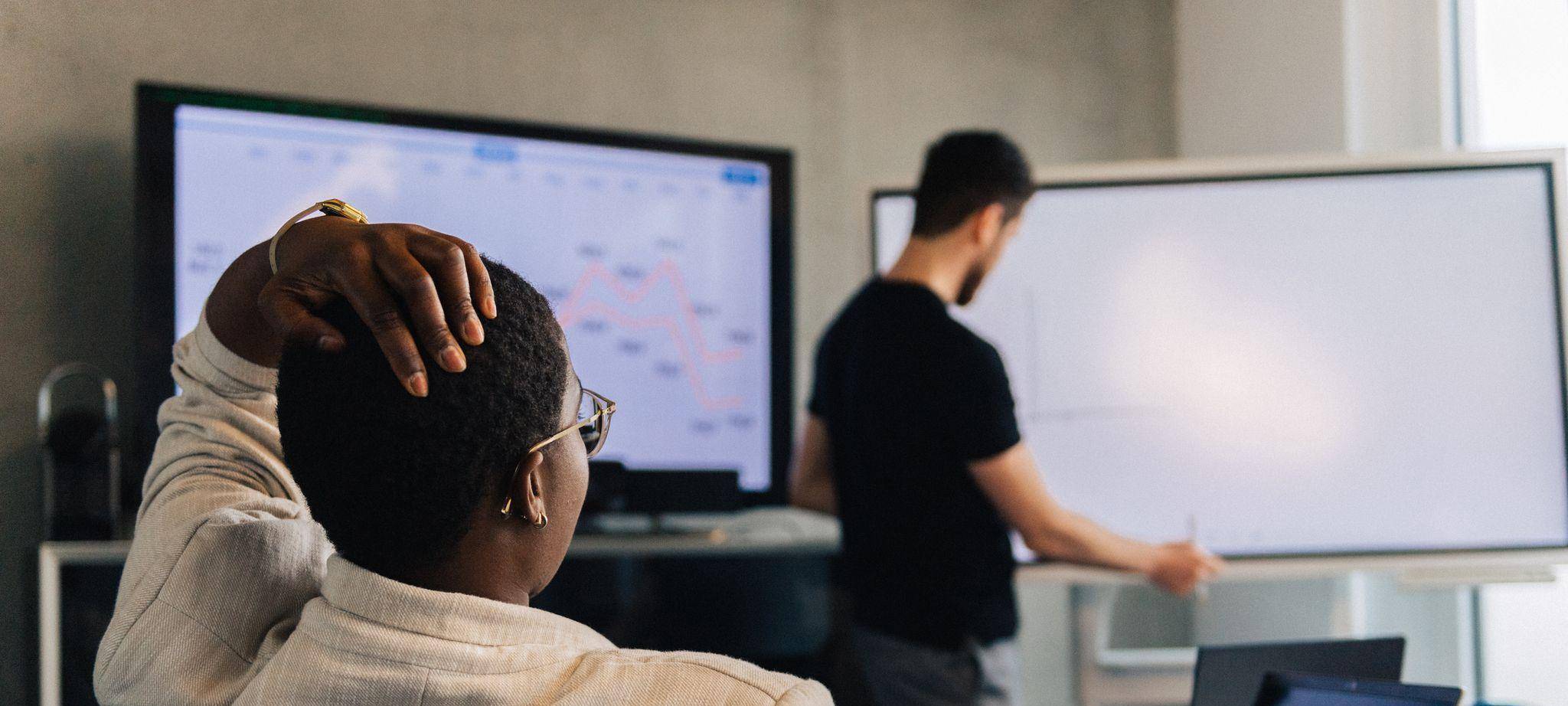 Eine Frau fasst sich an den Kopf in einem Meetingraum