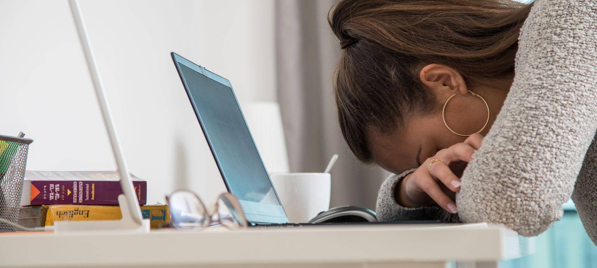 Eine junge Frau legt den Kopf auf den Tisch