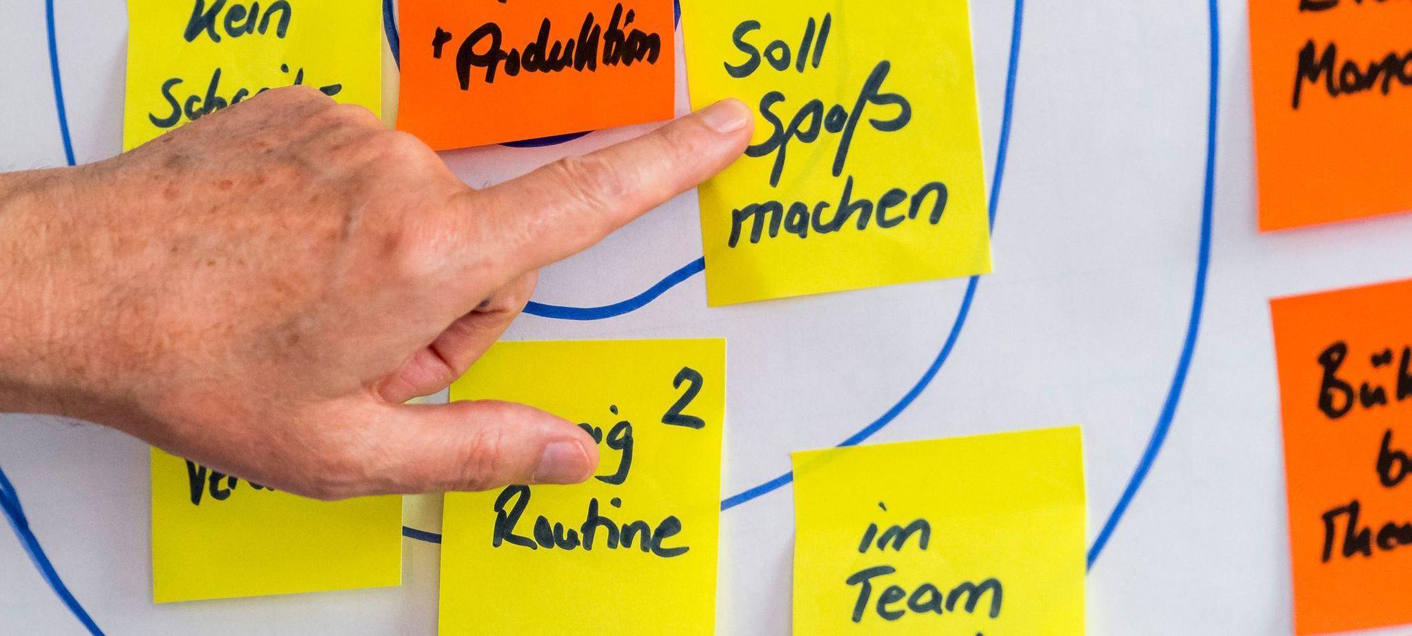 Eine Person klebt Post-its auf ein Flipchart