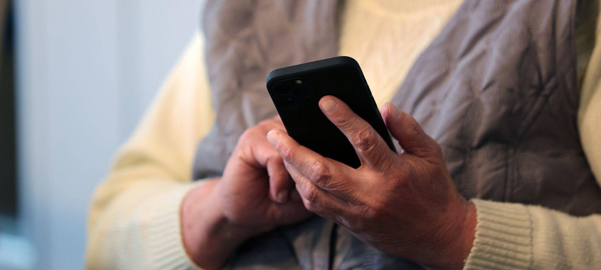 Eine Seniorin schreibt eine Nachricht in ihr Handy