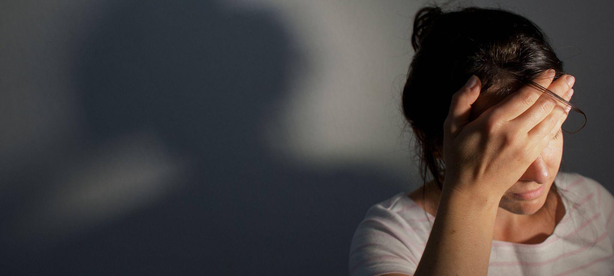 Frau fasst sich an die Stirn