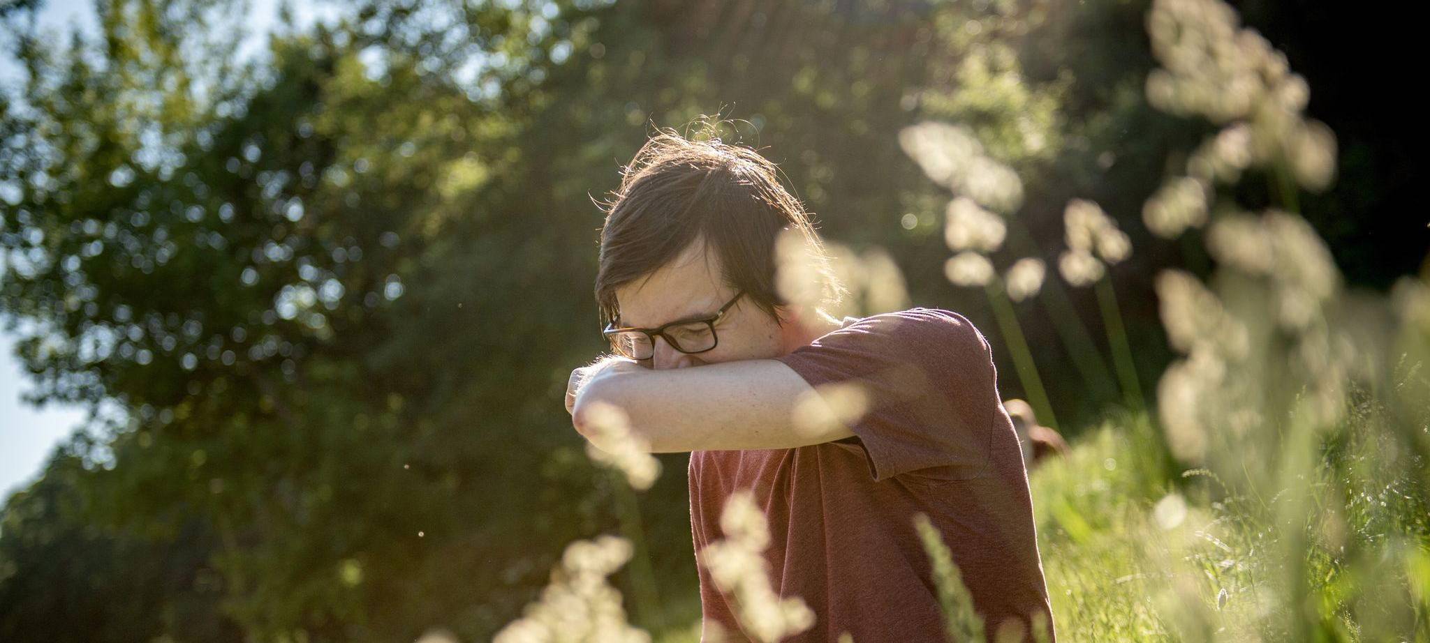 Mann in einem Park niest