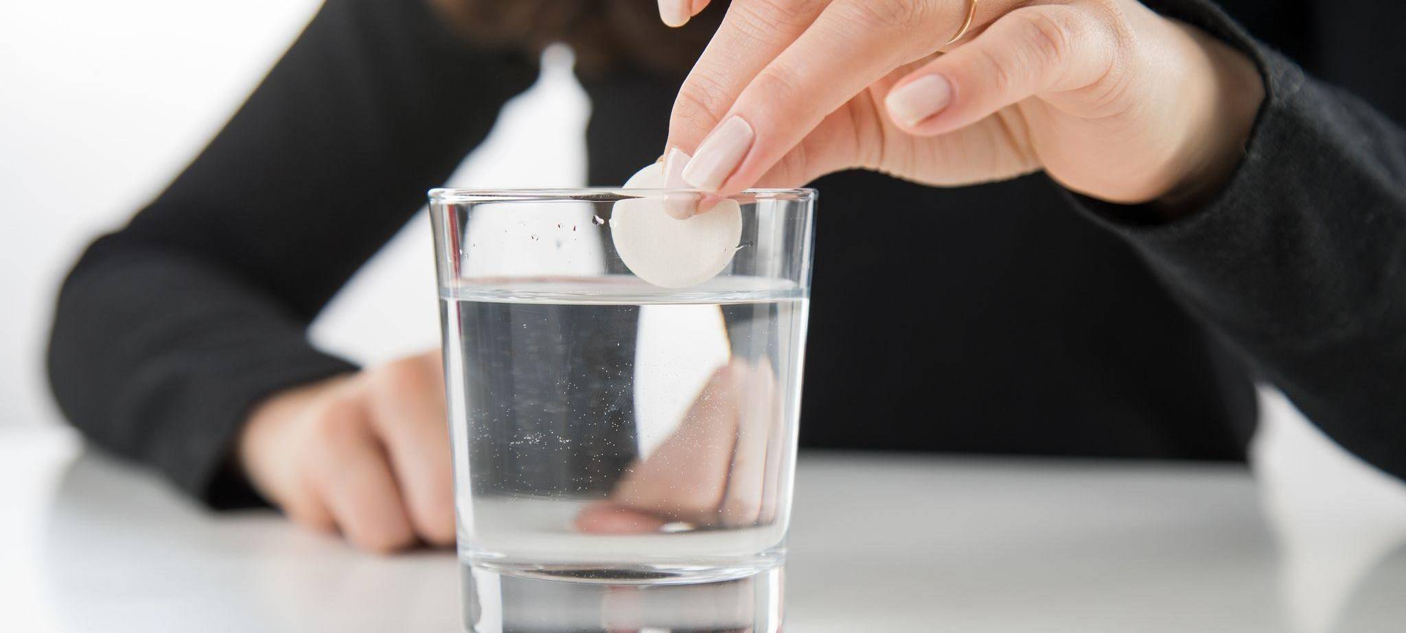 Brausetablette wird in ein Glas Wasser gegeben
