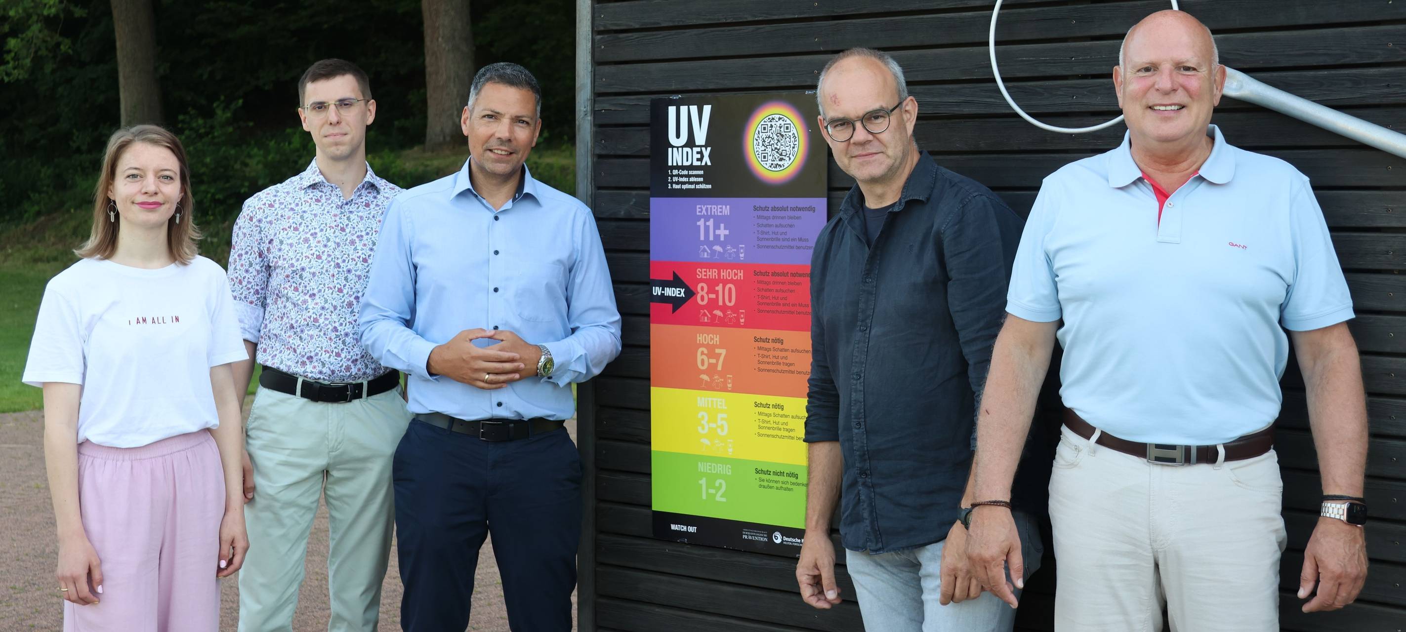 Karolin Wiegel (Klimafolgenanpassungsmanagerin), Leonard Wied (Abteilung Sport und Bäder), Stadtrat Adrian Viteritti, Christian Janusch (Kreissportbund Siegen-Wittgenstein) und Frank Wunderlich (Stadtsportverband Siegen) prüfen den UV-Wert im Geisweider Freibad.