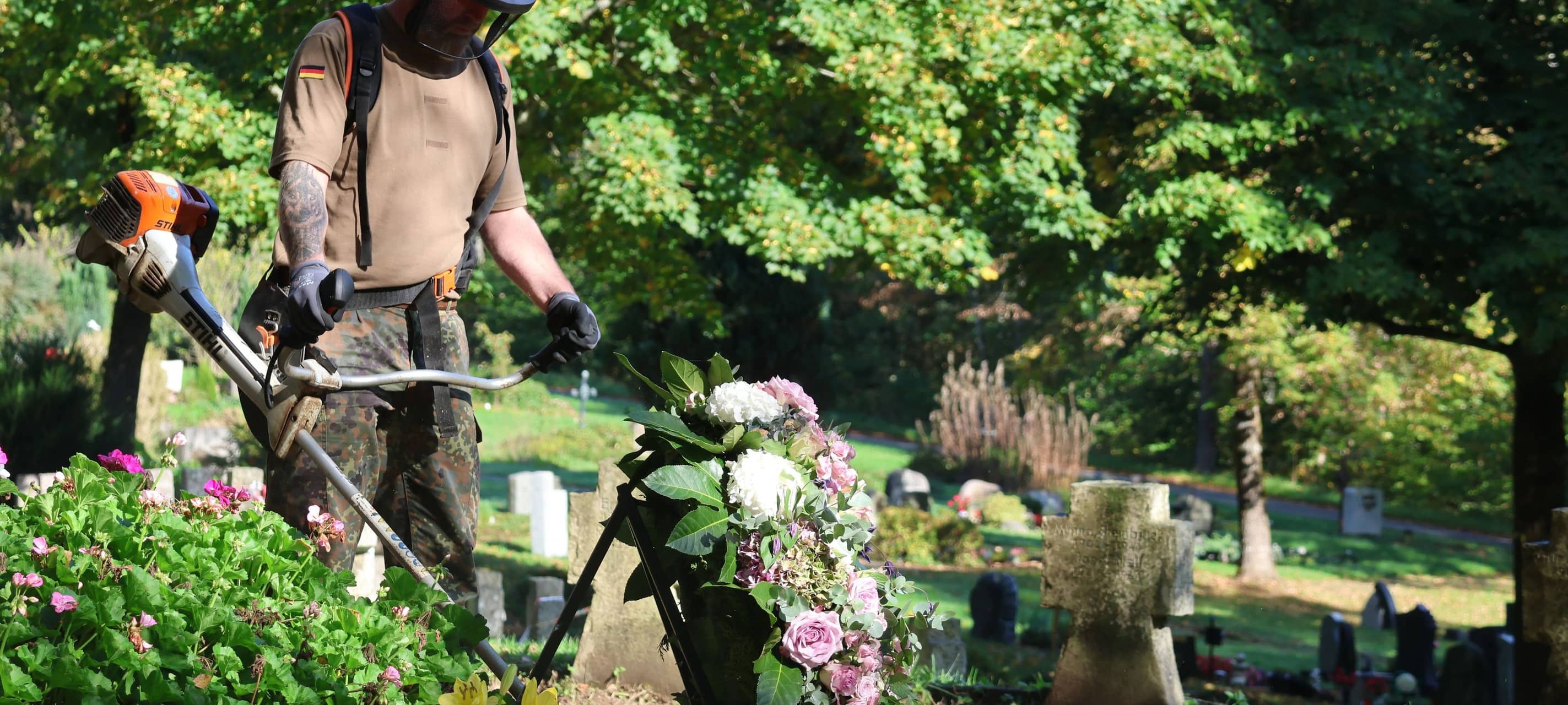 Ein Soldat mäht das Gras am Ehrenmal der zentralen Gedenkstätte am Hermelsbacher Friedhof.