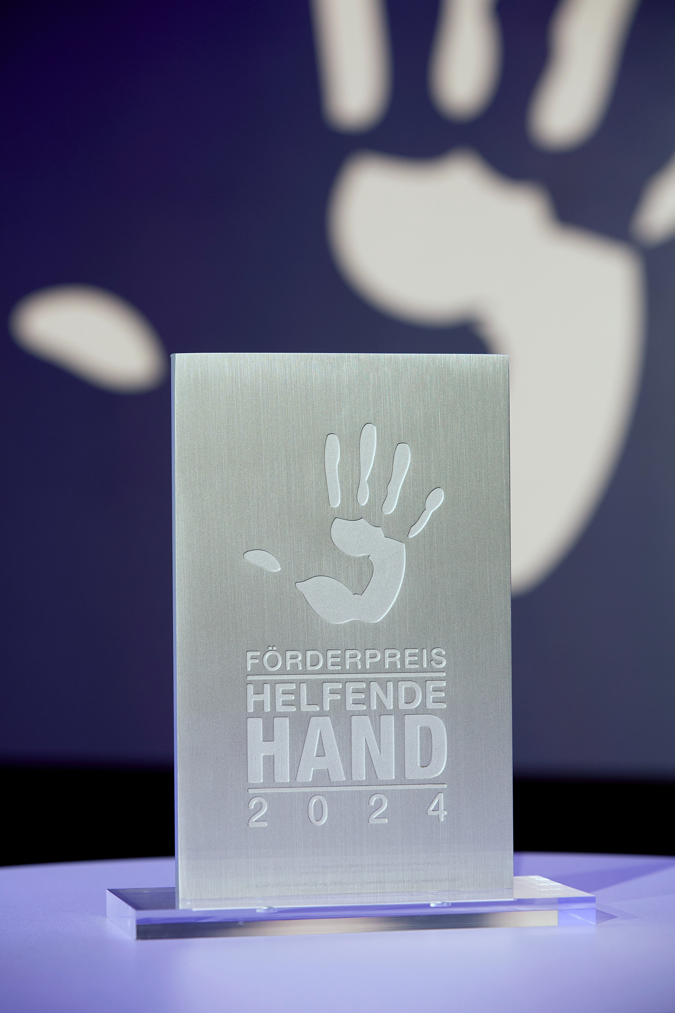 Silberne Preistafel mit einer Hand darauf.